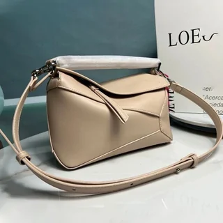 A beige leather shoulder bag with a geometric panelled body and a long strap, on a white surface