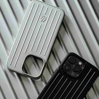 Two phone cases, one brushed silver and one black, resting on a ridged metal surface